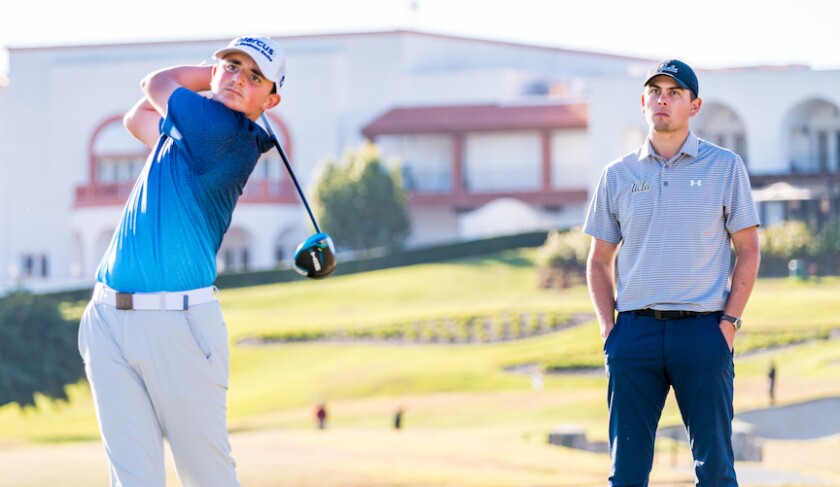 Young golfer strikes ball watched by coach