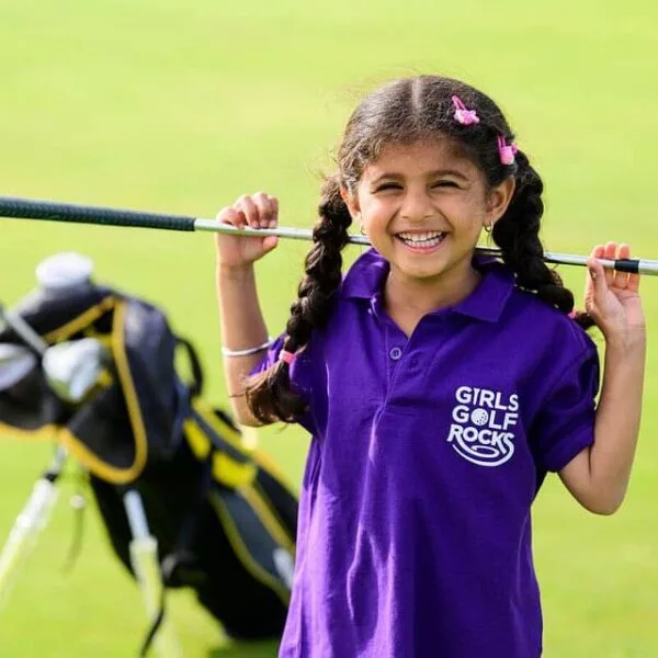 Young child smiles with golf club behind their head