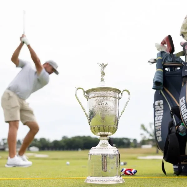 The US Open Championship Trophy is seen as Captain Bryson DeChambeau of Crushers GC hits his shot on the driving range