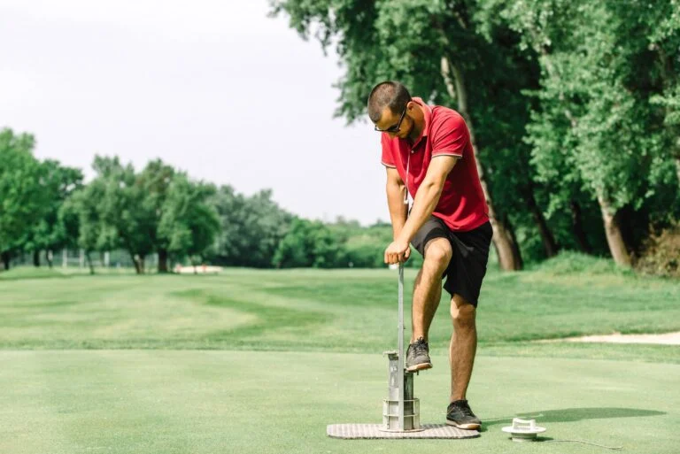 Golf course maintenance, greenskeeper cutting a golf hole